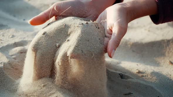 SLOW MOTION, CLOSE UP: The Sand Passes Through the Fingers of a Young Woman. The Sand Is Running alt