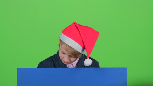 Teenager in the Hat Appears From a Board on a Green Screen alt