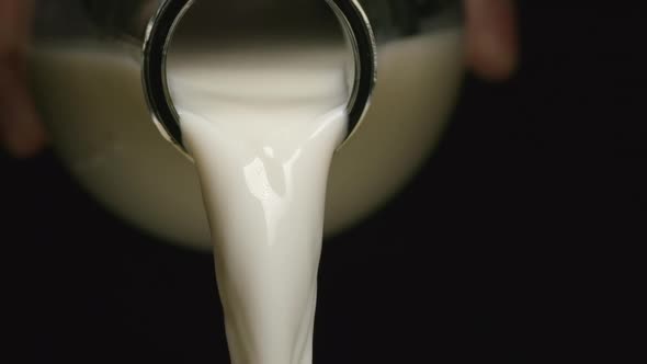 Milk flows from a neck of bottle - Human hand