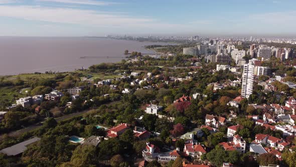 Aerial flyover San Isidro residential area in Buenos Aires with trees and river in background during alt
