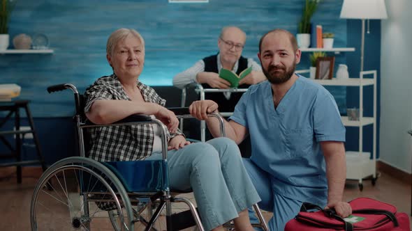 Portrait of Old Invalid Woman and Man Nurse Looking at Camera alt