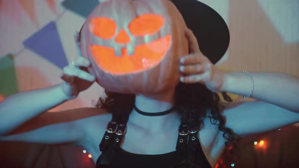 A Girl in a Creepy Costume with a Jacko'lantern Poses for the Camera on Halloween alt