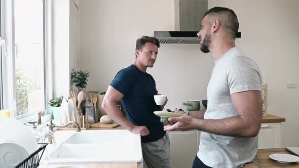 Gay male couple talking together at home in the morning during breakfast time