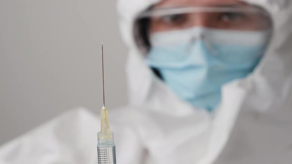 Vaccine in the Syringe for Prevention of Coronavirus in Doctor Hand Wearing Protective Mask and alt