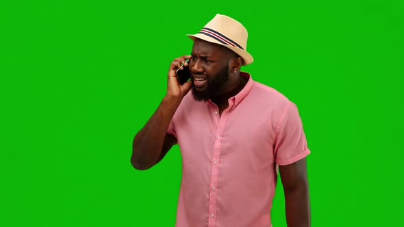 Angry man speaks on the phone. African american man in hat and pink summer shirt. Alpha channel