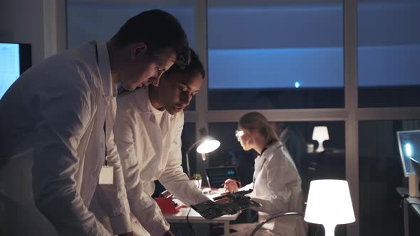 Side View of Two Electronics Development Engineers Talking About Electronic Board and Explaining alt