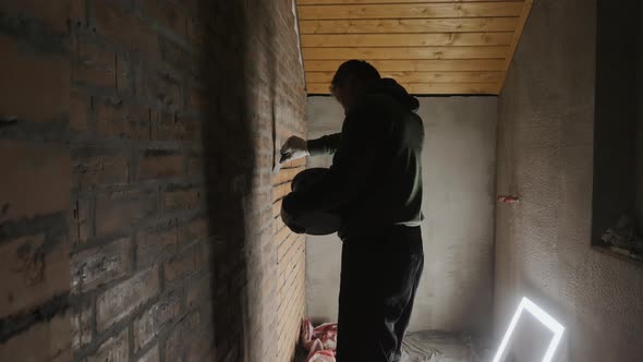 A Worker Covers Up Cracks in a Brick Wall with Cement
