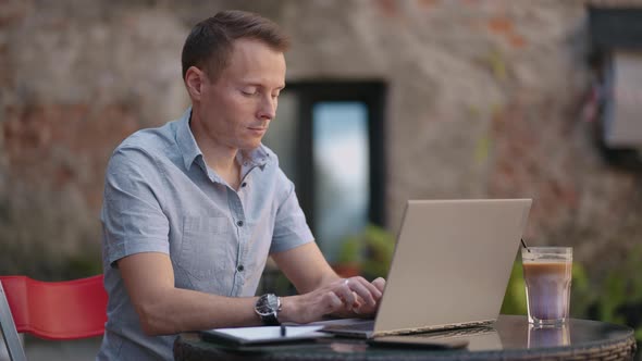 A Serious Man is a Business Student Working Studying Sitting at a Table and Typing a Message on a alt