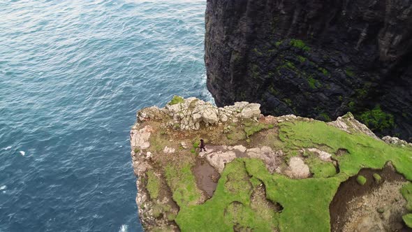 Aerial view of woman walking on the edge of tourists English Slave cliff. alt