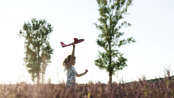 Happy Little Girl Playing With Airplane on a Lavender Field During Sunset