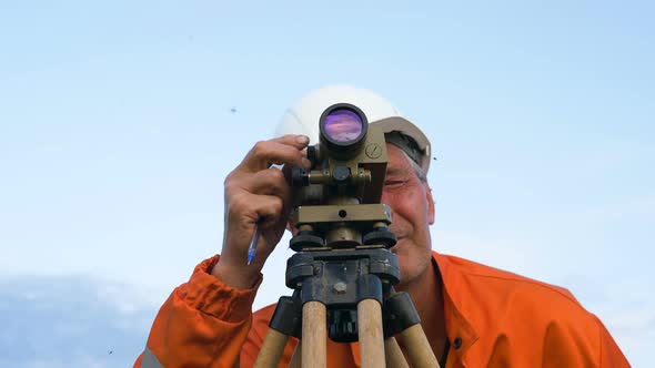 Concentrated Surveyor Looks Through Theodolite and Writes alt