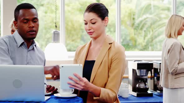 Business executives interacting with each other during break alt