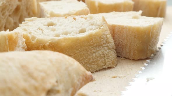 Long loaf of French baguette bread cutted on smaller pieces 4K 2160p 30fps UltraHD footage - Traditi alt