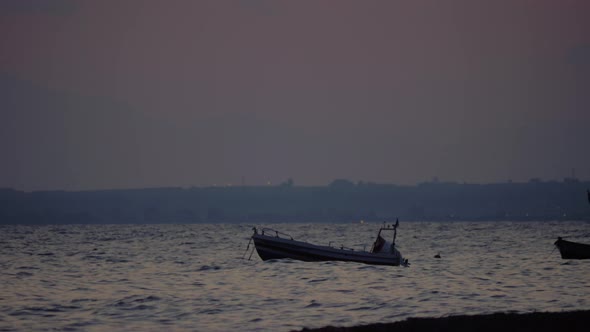 Evening scene of sea with moored boat rocking on waves alt