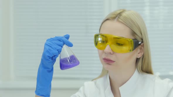 A Female Medical Or Scientific Researcher With Glasses And Latex Gloves Looking