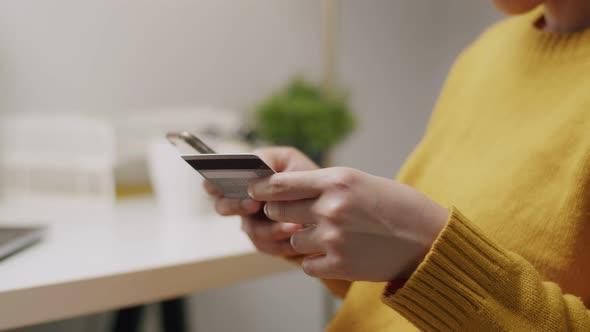 Close-up of an attractive young Asian woman using her cellphone for online shopping. alt