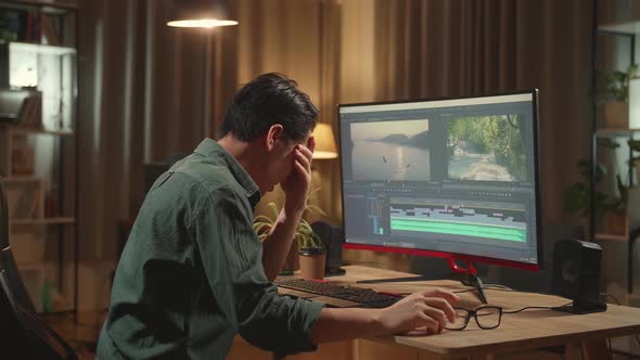 Tired Asian Male Video Editor Works With Footage And Sound On His Personal Computer alt