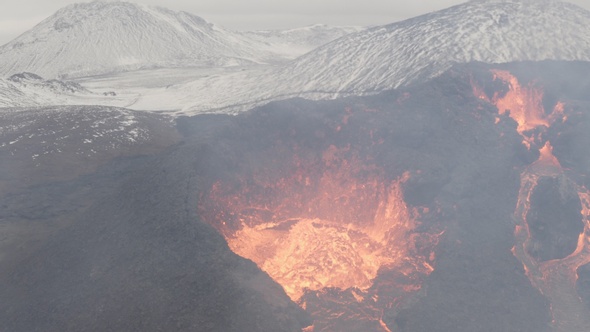 Flying Close to lava eruption volcano with snowy mountains alt