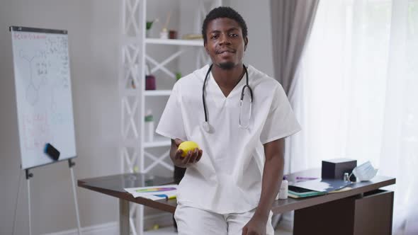 Cheerful Young African American Doctor Juggling Lemon Smiling Looking at Camera alt
