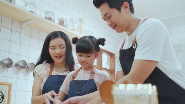 Asian happy family spending time in kitchen together while staying at home doing homemade bakery. alt