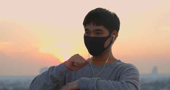 Asian man wearing face mask listening to music on earphones and dancing