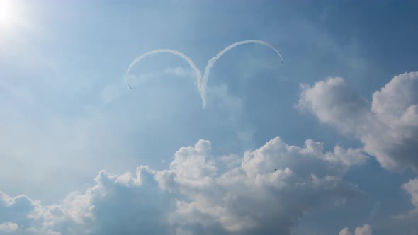 Group of three planes fulfills aerobatic figure of the heart in a cloudy sky with smoke
