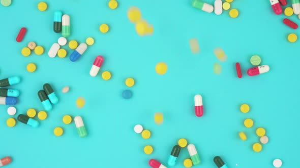 Colorful assorted medicines falling on light blue background, top view