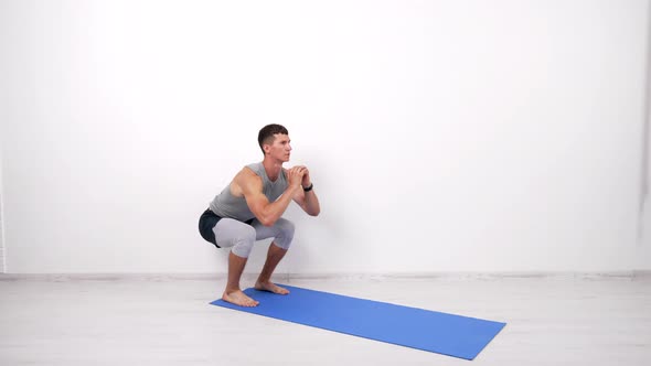 Athlet Muscular Guy Doing Squats Exercise on Fitness Mat White Background Keep Fit alt