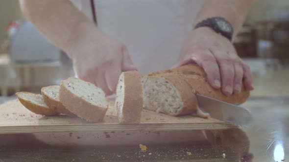 Baker is Cutting Baked Dutch Bread with Raisins and Dried Apricots with Knife alt