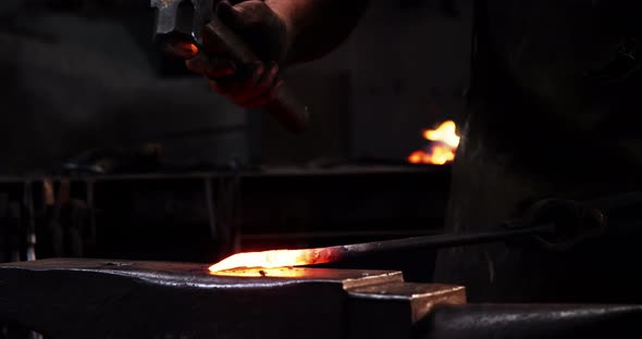 Mid-section of blacksmith working on a iron rod alt