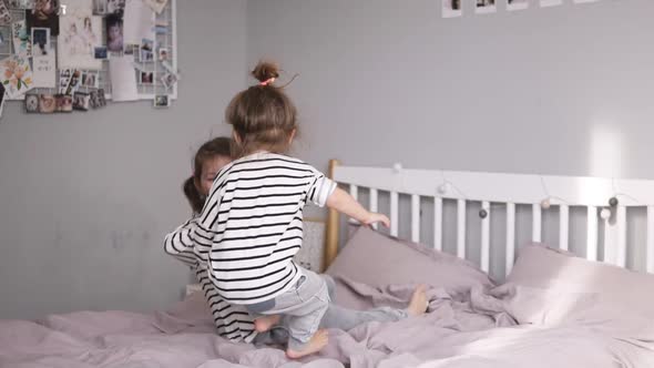 Two Little Sisters are Jumping on a Bed and Falling on It alt