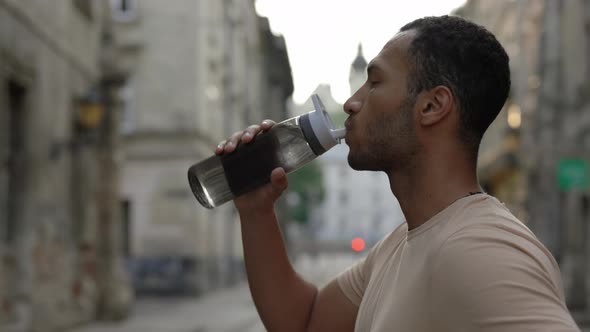 Side View African American Runner Drinking Water From the Sport Bottle After the Scamper alt