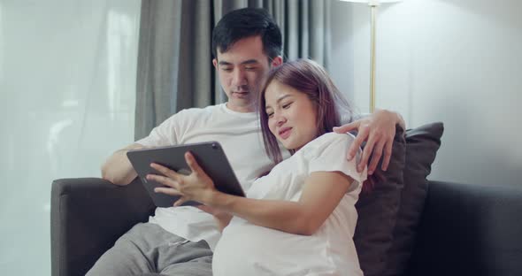 Happy caucasian husband with a pregnant wife looking ultrasound photo of her newborn baby.