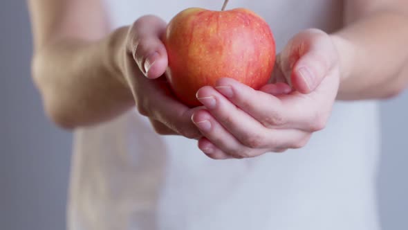 Closeup Image of a Woman Holding and Giving a Red Apple alt