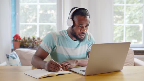 Focused African Businessman Wear Headphones Study Online Watching Webinar alt