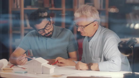 Two Mixed-Aged Male Architects Discussing Construction Plan alt