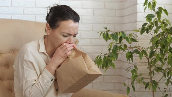 Sick woman breathe into the bag. alt