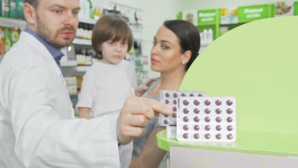 Pharmacist Giving Blister with Pills To a Little Boy and His Mother