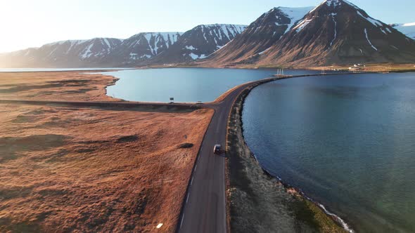Drone Of Car Driving On Road Over Fjords Towards Mountains alt