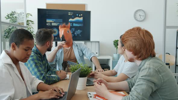 Guy Wearing Horse Mask Leading Business Meeting Talking to Employees Then Leaving Office alt