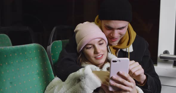 Beautiful Girl Scrolling Smartphone While Leaning on Her Handsome Boyfriend. Cheerful Young Couple alt