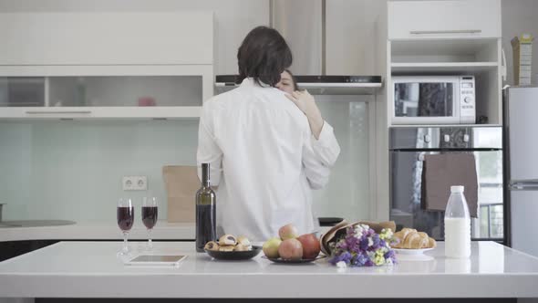 Romantic Slow Dance of Happy Young Caucasian Couple in Kitchen at Home. Smiling Carefree Boyfriend alt