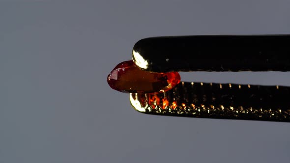 Natural Hessonite Brown Garnet Gemstone in the Tweezer on the Turn Table alt