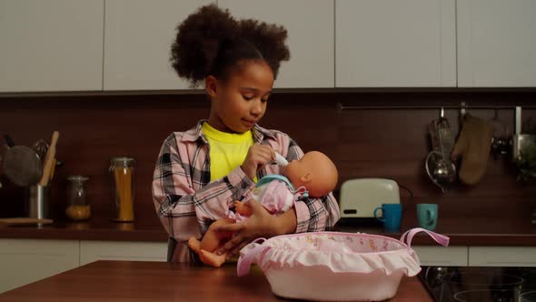 Cute School Age African American Girl Playing Mother with Doll Indoors alt