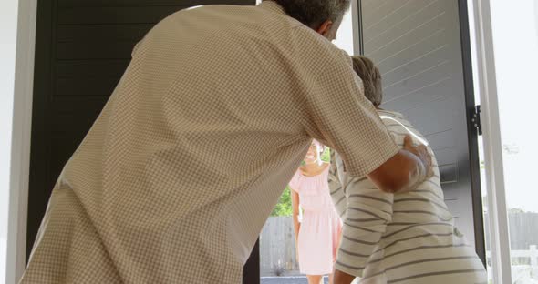 Rear view of senior black couple welcoming children at door in a comfortable home 4k alt