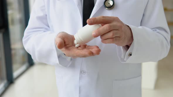 Senior Doctor Pouring Pills From Bottle alt