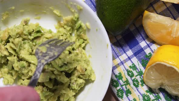 Mixing the Sliced Avocado in a White Bowl Close-up. Vegan Healthy Snack, Against the Background of