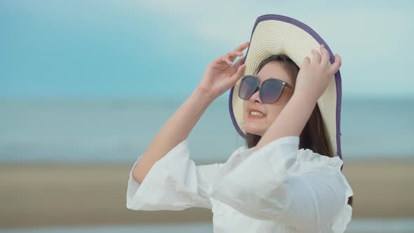 Cute Asian girl walking on the beach by the beach. She turned to smile at the camera.