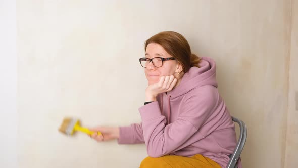 A Bored Girl Lazily Smears the Wall with Wallpaper Paste