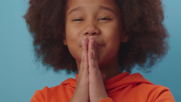 Close up of African American girl holding hands folded begging about something looking at camera alt